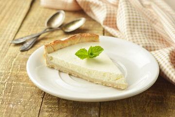 Slice of plain cheesecake on wooden table. Homemade dessert.