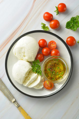 Mozzarella cheese and cherry tomatoes with spices. Homemade mozzarella cheese.