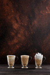 Obraz na płótnie Canvas Three cups of coffee at wooden table background. Vertical image with free space.