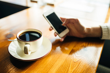 Woman using smartphone on wooden table in cafe. Close-up image with social networks concept