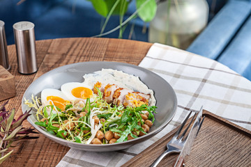 Close up view on turkey salad with chickpeas served in bowl on wooden table. Healthy food, dieting. Copy space for design. Picture for recipe, menu.