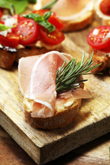 antipasto various appetizer. Cutting board with prosciutto, salami, cheese, bread and olives on dark wooden background