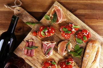 antipasto various appetizer. Cutting board with prosciutto, salami, cheese, bread and olives on dark wooden background