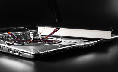Eyeglasses with book on laptop keyboard.