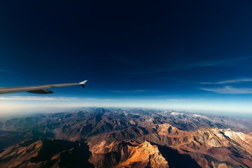 Aerial view of the Andes mountain range with plane wing, on the border between Chile and Argentina