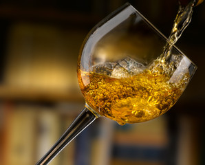 vino bianco versato in un calice, sfondo libreria
