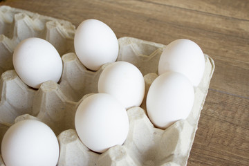 White chicken eggs in a cardboard tray. Egg tray on wooden background