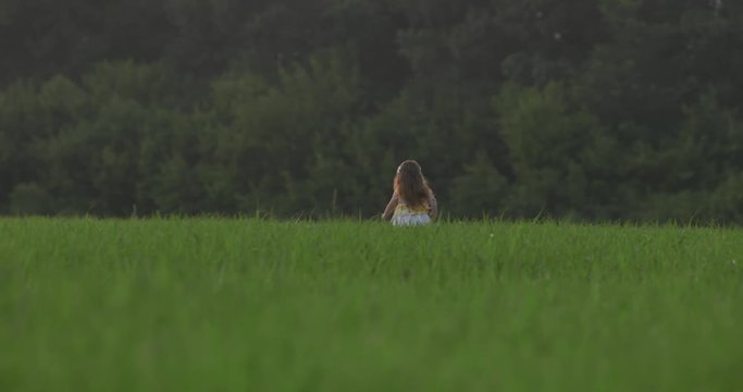 Girl runs away in a field of wheat