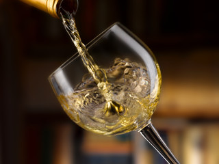 vino bianco versato nel bicchiere,sfondo libreria