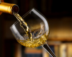 vino bianco versato nel bicchiere,sfondo libreria