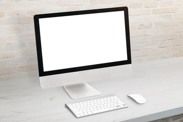 Computer display on white desk. Keyboard and mouse beside. Modern office brick wall in background. Isolated screen for mockup, app or website presentation.