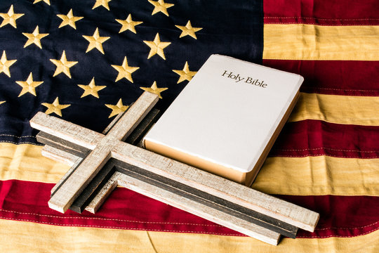 wood cross and white bible on old looking tea stain american flag