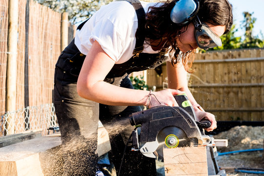 Carpenter cutting piece of wood with circular saw
