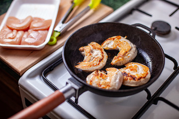Closeup of chicken meat strips cooking on a hot pan on a gas stove