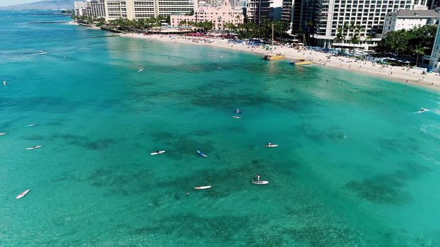 Slowly flying in a circle over paddle boards and soft waves outside Waikiki beach, Hawaii.