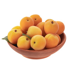 heap of apricots with green leaves  in wooden cup isolated on white background