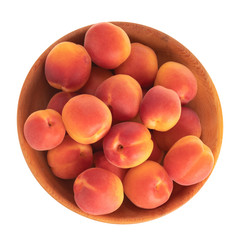 heap of red apricots in wooden plate isolated on white background. top view