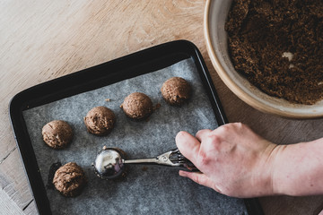 High angle close up of person putting chocolate cookie dough on a baking tray.