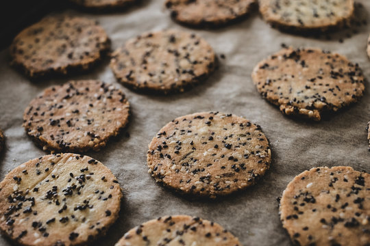 High angle close up of freshly baked seeded crackers on a baking tray.