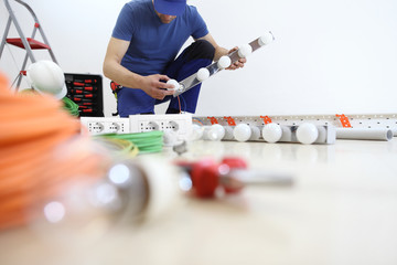 electrician at work installing lamp, with bulb in hand, install electric circuits, electrical wiring