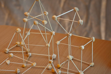 The atom model is made of supportive materials. Molecular grid of toothpicks and nuts. School...