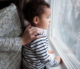 Side view of mother and son looking through window at home