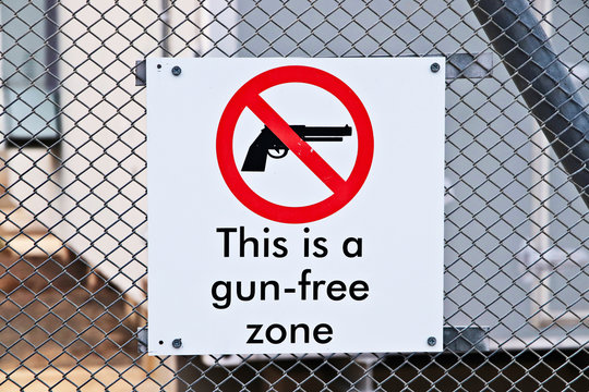 A Gun-free zone signpost on a fence. Gun control in America concept image. 