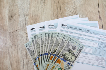 tax forms 1040 and dollars on wooden background