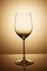 an elegant empty glass of wine  is standing opposite the light