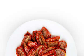 Dried tomatoes on a white background. Slices of dried tomatoes in oil on a plate.