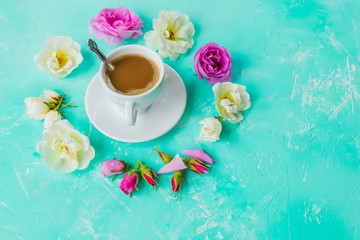 Obraz na płótnie Canvas Delicious fresh morning espresso coffee with a beautiful thick crema on the azure colored table background with misty bubbles rose buds on it, flat lay.cup of coffee , roses flowers.Copy space
