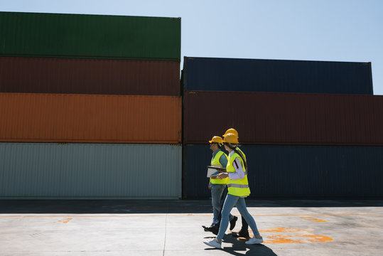 Workers walking together near stack of cargo containers on industrial site