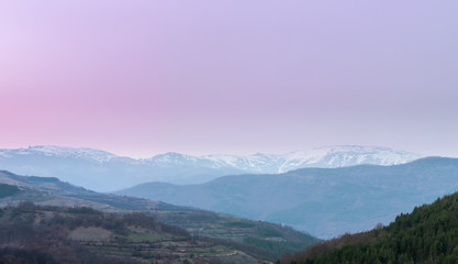 Soft, colorful, blue hour view of distant, snow capped summits Midzor and Babin Zub, the highest on Old mountain in Serbia