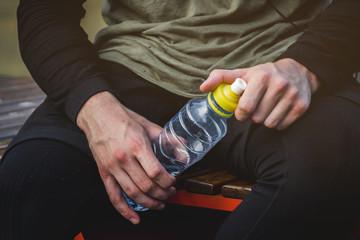 bottle of water in the hands of a male athlete on the sports field