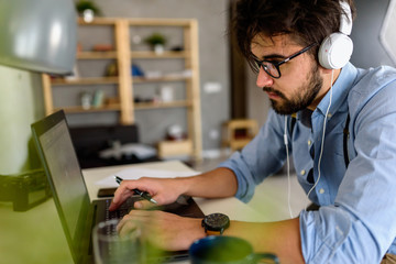 Young modern bearded man working with laptop computer indoors