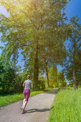 Young woman goes running in a beautiful park in the afternoon sun