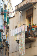 Multicolored laundered clothes are dried on the balcony in the alley of Naples, self-catering and environmental friendliness