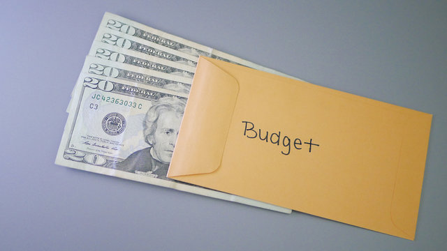 A yellow envelope on a gray table, containing cash for personal budget, budgeting expenses.
