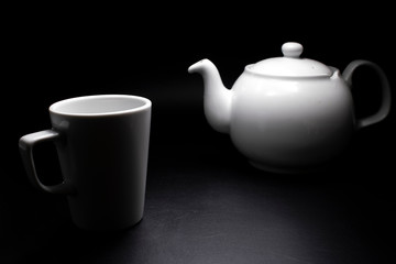 White porcelain teapot and cups. Traditional design. Black background.