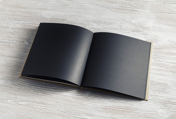 Opened blank black brochure on light wood table background. - obrazy, fototapety, plakaty