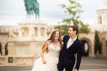 Naklejka premium Young beautiful stylish pair of newlyweds walking by the Fisherman's Bastion in Budapest, Hungary