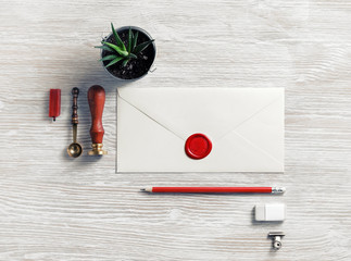 Blank retro envelope with red wax seal and retro stationery on light wood table background. Mockup for your design. Flat lay.