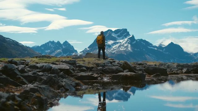 Hiker with backpack walks through snow capped mountains