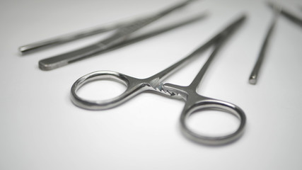 A pair of stainless steel surgical clamps and medical grade pointed probes on a white table.