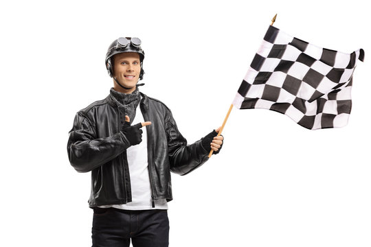 Young male biker waving a checkered race flag and pointing