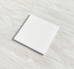 Blank square notebook on light wood table background. White paper notepad.