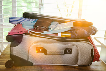 Full suitcase packed for vacation without more space and sunbeams from window