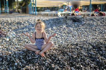 Funny girl in striped swimsuit on pebble beach