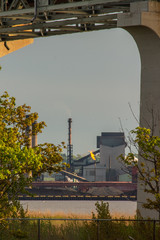 View of a Steel Mill Framed By a Bridge Support