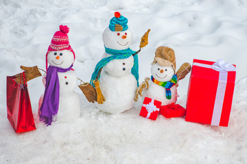 Snowman - father, mother and snowman - baby surprise outdoor. Snowman - parent and snowman kid with shopping bag - gift shopping concept.